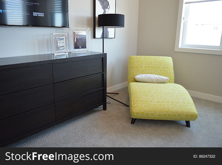 An room in an apartment with an yellow lounge chair in the corner.