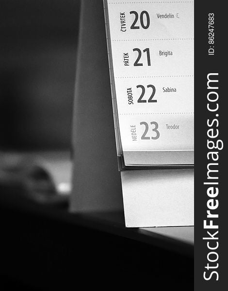 A black and white close up of a calendar on a desk. A black and white close up of a calendar on a desk.