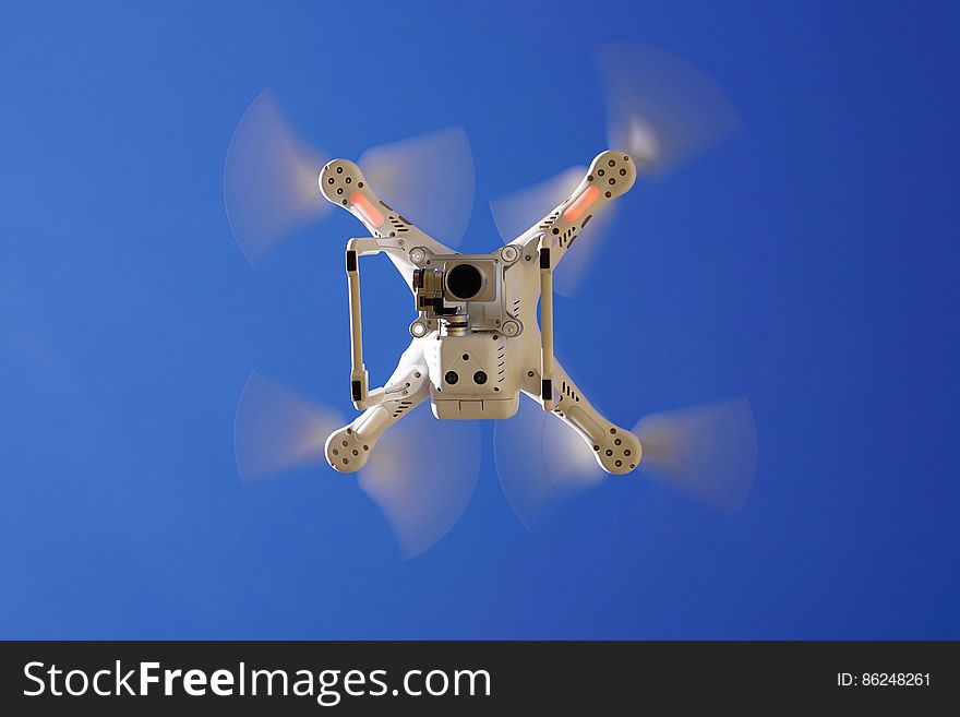 Drone flying overhead against blue skies on sunny day. Drone flying overhead against blue skies on sunny day.