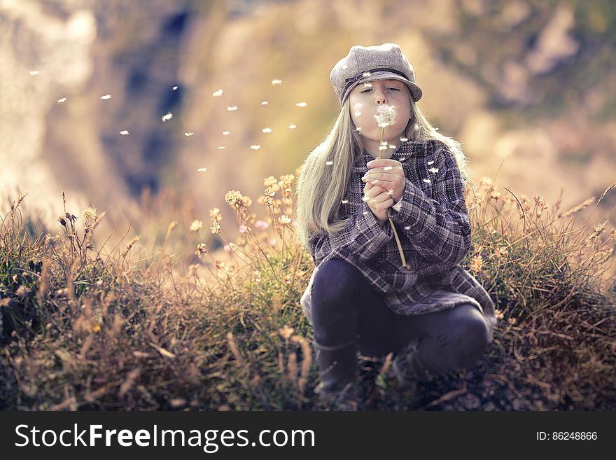 Girl blowing dandelions in field