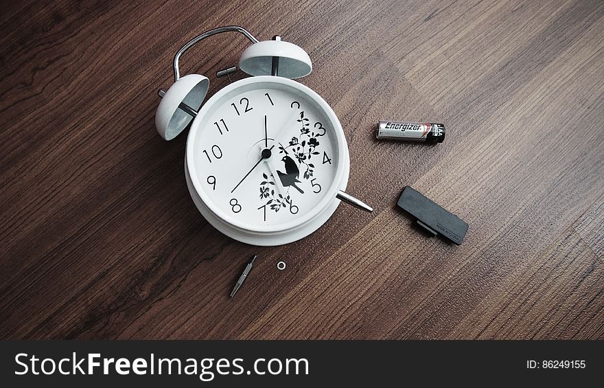 Alarm clock lying on wooden table with battery removed. Alarm clock lying on wooden table with battery removed.