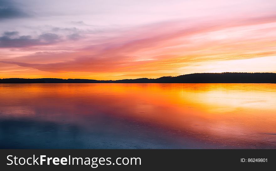 A sunset over a calm lake. A sunset over a calm lake.
