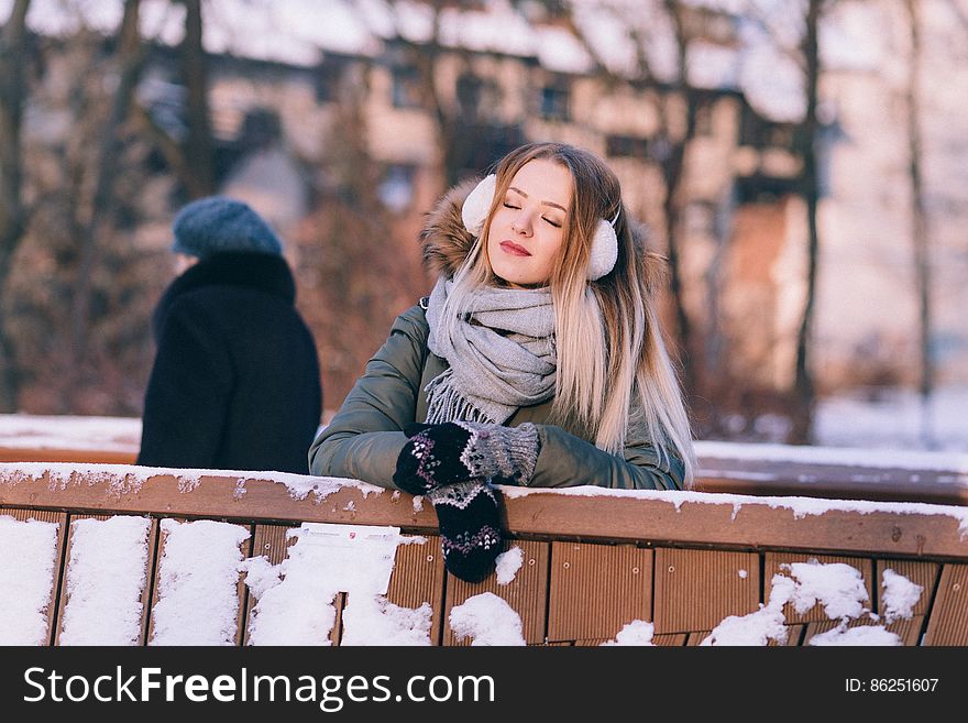 Young Woman Sitting On Bench In Winter