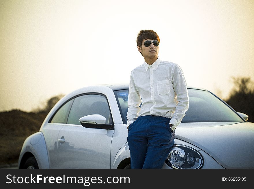 Man in White Button Down Shirt Leaning on Silver Beetle Car