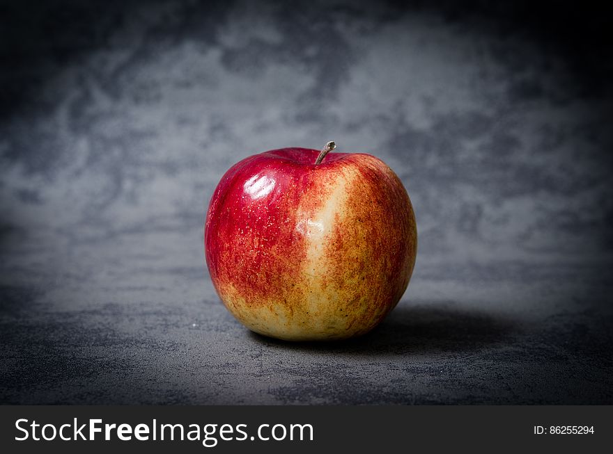 A close up of a ripe apple on a gray background.