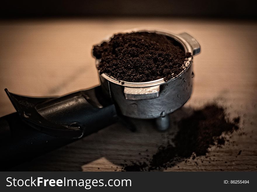 Close up of coffee grounds in espresso basket on wooden tabletop. Close up of coffee grounds in espresso basket on wooden tabletop.