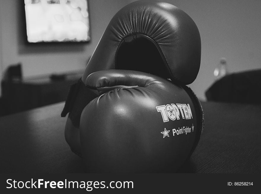 Black and white closeup of Top Ten brand boxing gloves on table. Black and white closeup of Top Ten brand boxing gloves on table.