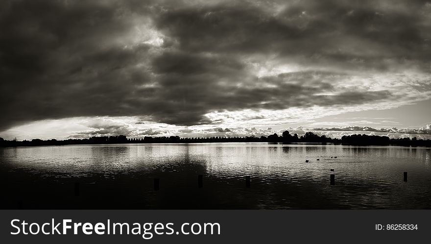 Sunset behind clouds over water in black and white. Sunset behind clouds over water in black and white.