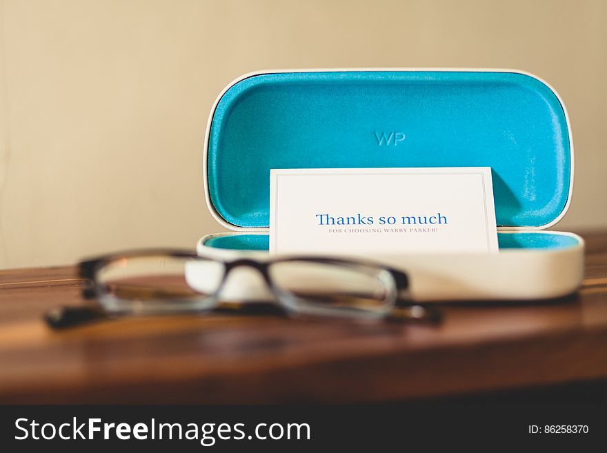 Eyeglasses on wooden table with open case holding thank you note. Eyeglasses on wooden table with open case holding thank you note.