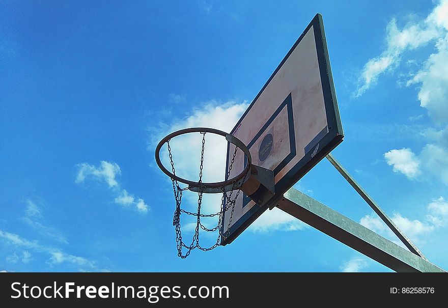 Low angle view of outdoor basketball backboard with blue sky and cloudscape background. Low angle view of outdoor basketball backboard with blue sky and cloudscape background.