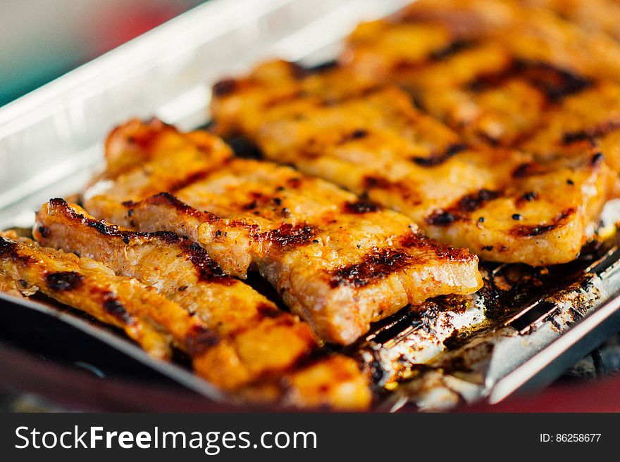 Close up of pieces of grilled pork on metal grate platter. Close up of pieces of grilled pork on metal grate platter.