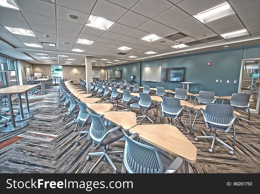 Brown Wooden Triangular Tables And Gray Rolling Chairs Inside Room