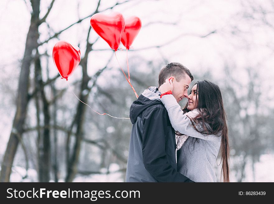 Two People With Heart Shape Balloons in Winter