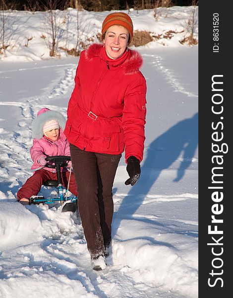 Mother pulls daughter on snow scooter