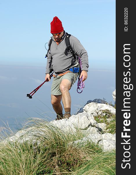 A handsome middle age hispanic latin man in a top of a in mountain hiking with a backpack. A handsome middle age hispanic latin man in a top of a in mountain hiking with a backpack