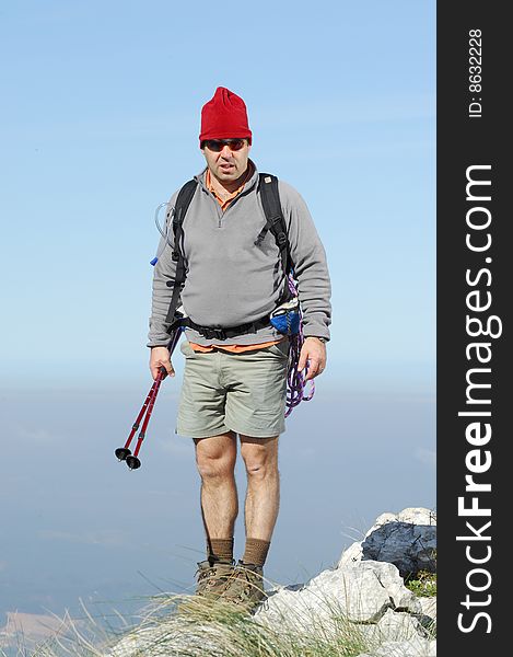 A handsome middle age hispanic latin man in a top of a in mountain hiking with a backpack. A handsome middle age hispanic latin man in a top of a in mountain hiking with a backpack