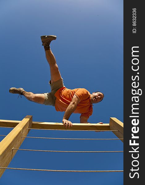 A sporty young male jumping over a wooden fence, under a clear blue sky. A sporty young male jumping over a wooden fence, under a clear blue sky