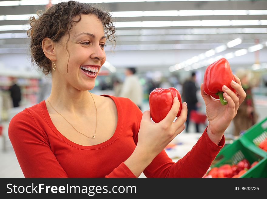 Young woman in shop with red sweet peppers