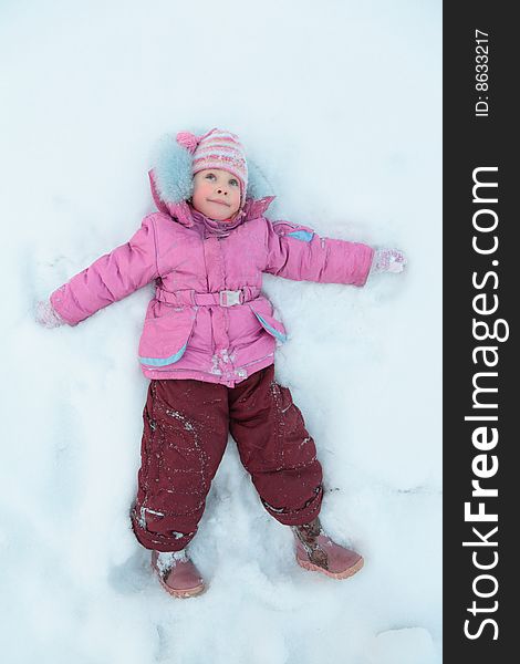 Little girl lying on snow, winter