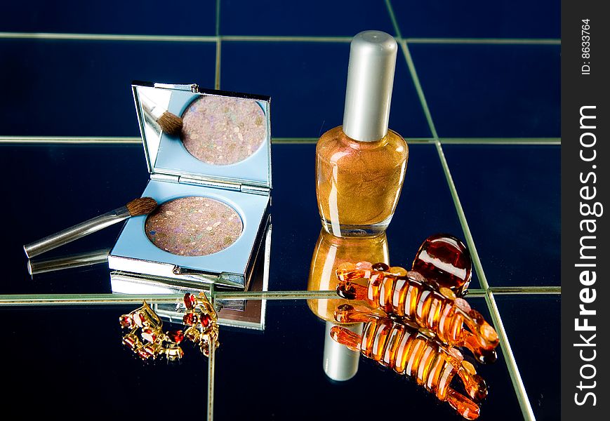 Cosmetics and golden jewellery on mirrors. Cosmetics and golden jewellery on mirrors