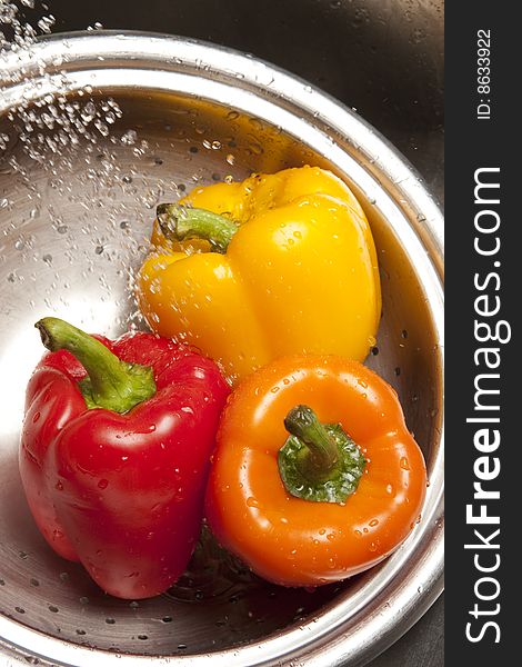 Yellow, red, and orange bell peppers washed in stainless steel metal collinder. Yellow, red, and orange bell peppers washed in stainless steel metal collinder