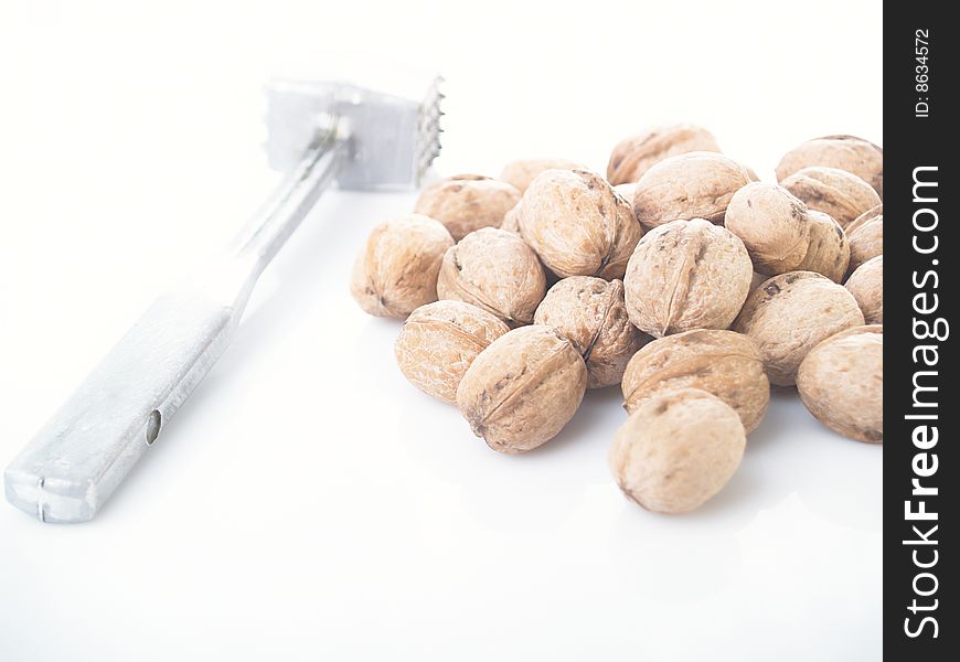 Walnuts and hammer on a white background