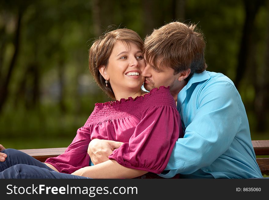 The married couple kisses in a summer garden. The married couple kisses in a summer garden