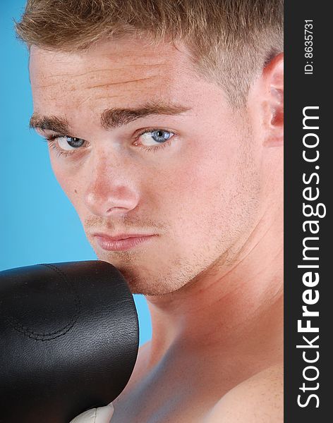 Young adult with boxing gloves against blue background. Young adult with boxing gloves against blue background