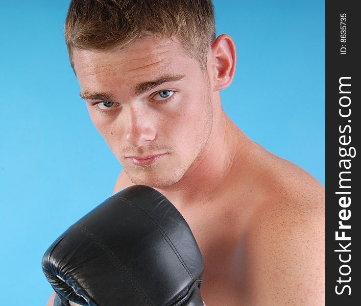 Young adult with boxing gloves against blue background. Young adult with boxing gloves against blue background