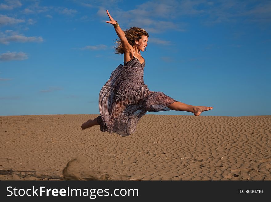 Young happy woman jumping in the sand