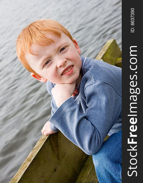 Boy on the edge of a wooden jetty over water. Boy on the edge of a wooden jetty over water