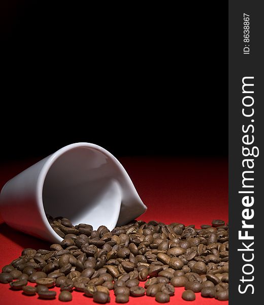 A fallen cup with coffee beans spread out.