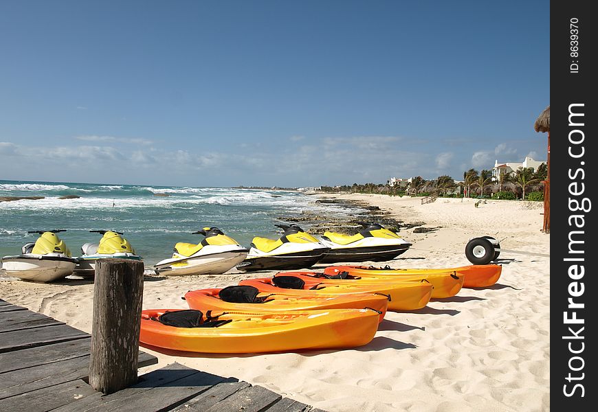 Kayaks and seadoos waiting for action on the beach of a mexican resort. Kayaks and seadoos waiting for action on the beach of a mexican resort.