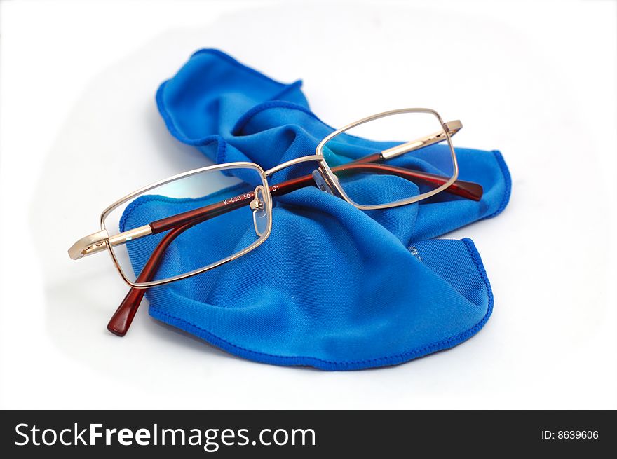 Style glasses lying on a blue scarf isolated on white. Style glasses lying on a blue scarf isolated on white