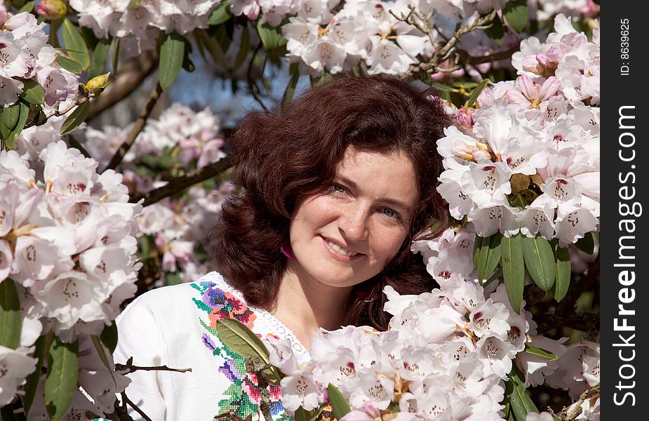 Smiling girl in flowering rhododendron bush. Smiling girl in flowering rhododendron bush