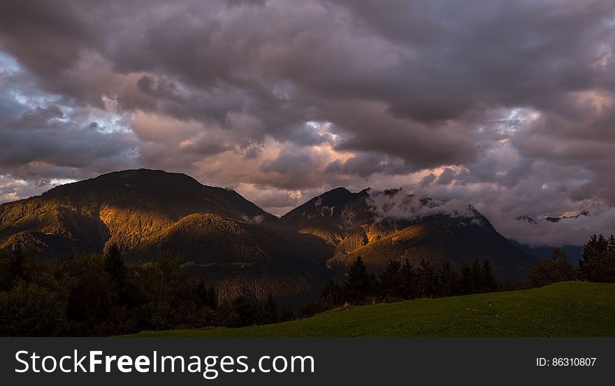 Dawn Through Clouds Over Mountain Peaks