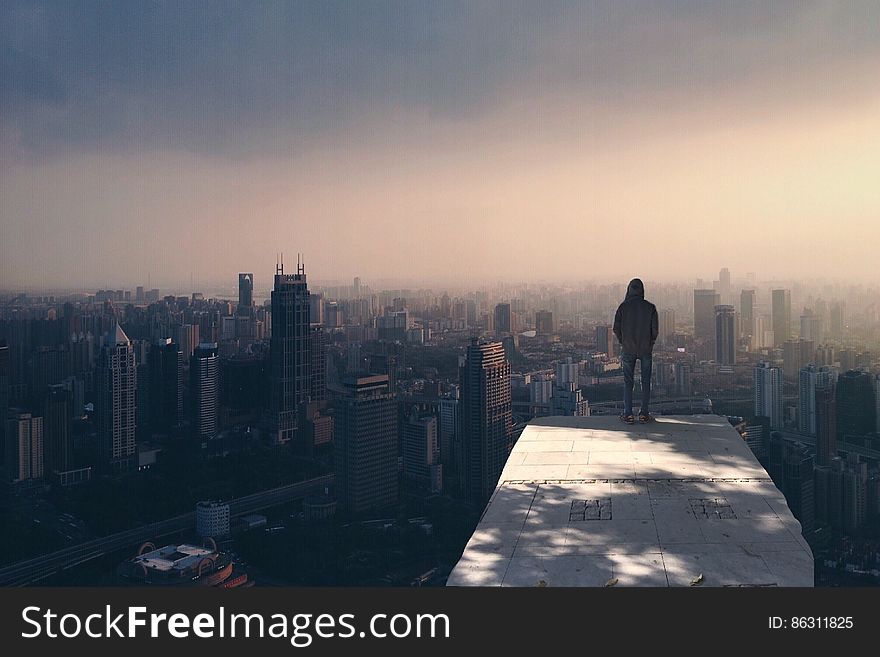 Man standing on rooftop overlooking skyline of city at daybreak. Man standing on rooftop overlooking skyline of city at daybreak.