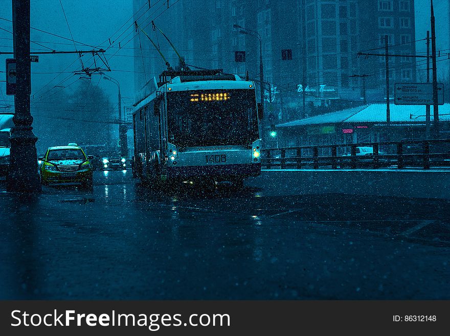 Tram on city streets with traffic in rain at night. Tram on city streets with traffic in rain at night.