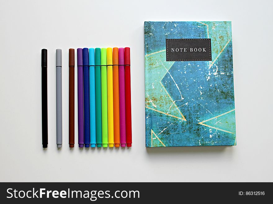 Colorful notebook with colored marker pens on white. Colorful notebook with colored marker pens on white.