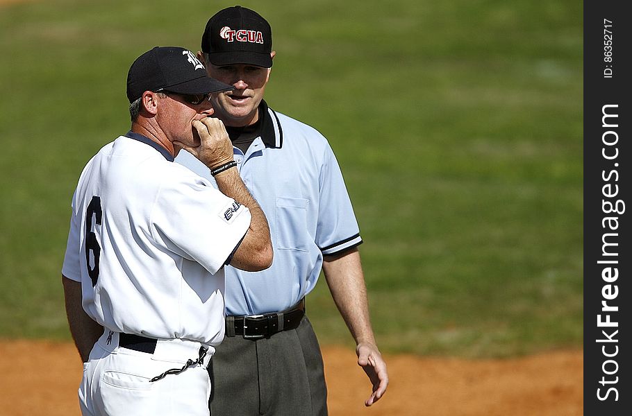 Baseball player talking to umpire or coach on field during game on sunny day. Baseball player talking to umpire or coach on field during game on sunny day.