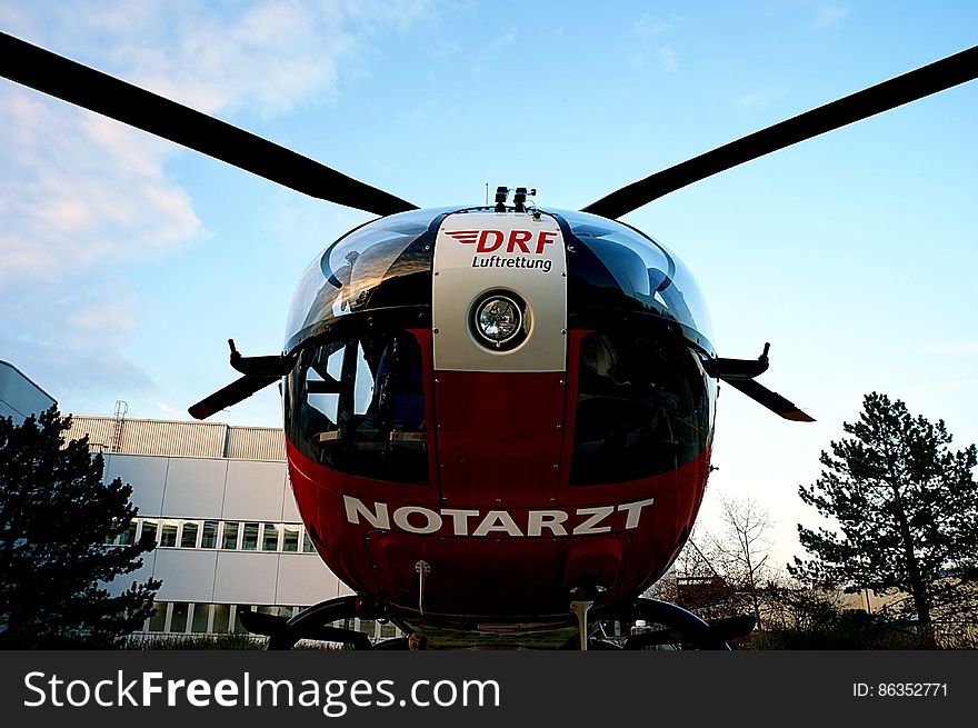 Helicopter parked on lawn outside hospital building on sunny day. Helicopter parked on lawn outside hospital building on sunny day.