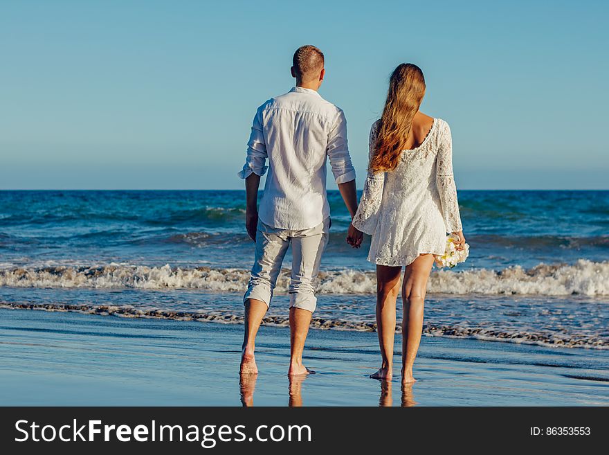 Rear View of Couple on Beach Against Clear Sky