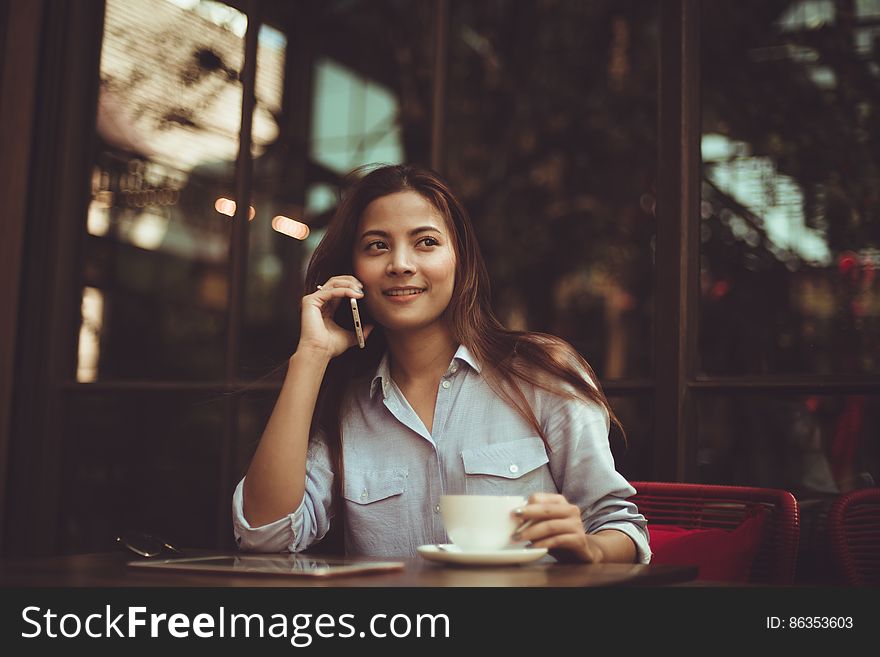 Portrait Of Young Woman Using Mobile Phone In Cafe