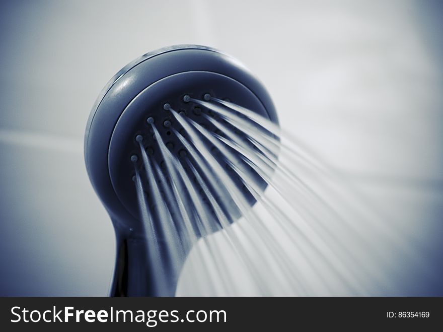 Close up a shower head spouting water.