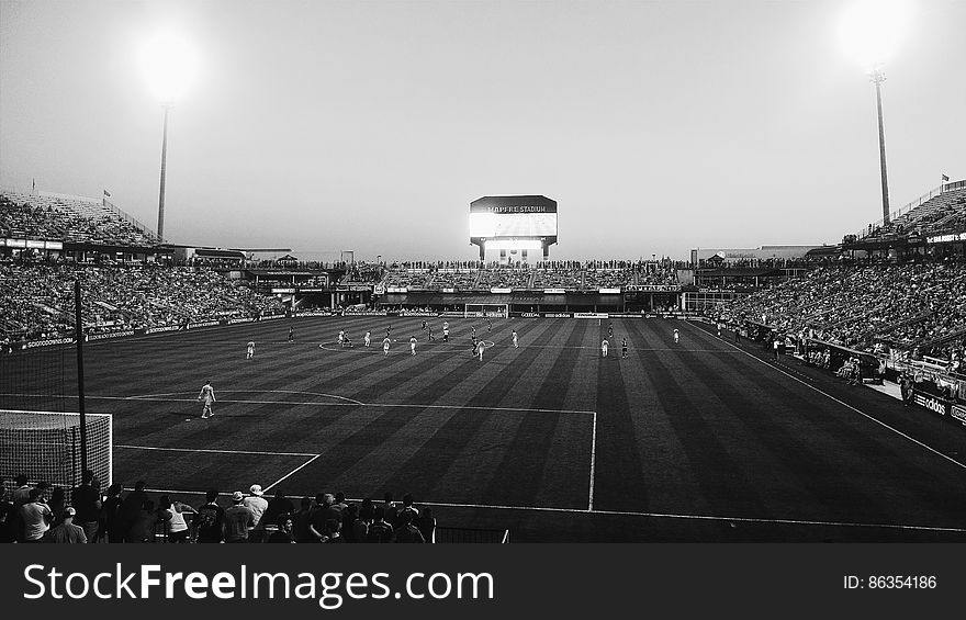 A black and white photo of a football stadium with an ongoing game.