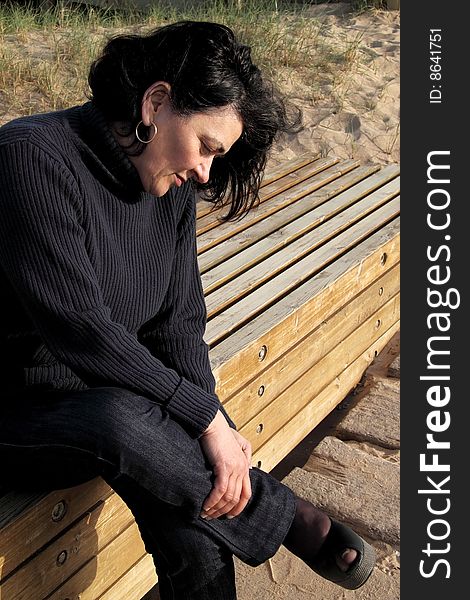 Woman Resting On The Seat Next To The Sandy Beach