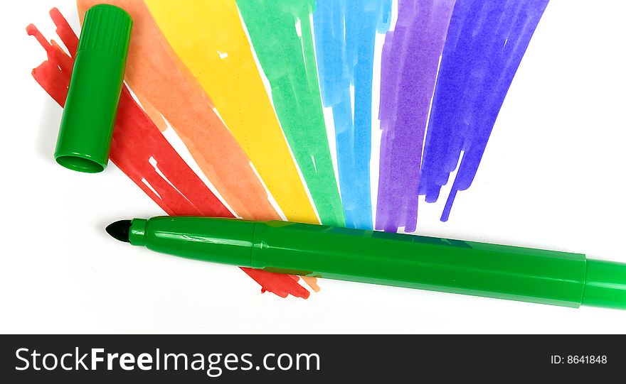 Dark green felt-tip pen with removed cap on a background of the drawn rainbow close-up