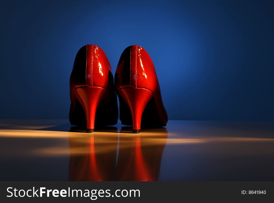 Pair of high heel red shoes on blue background, close up. Pair of high heel red shoes on blue background, close up