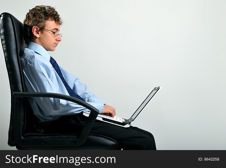 Young businessman sitting on office chair and using laptop. Young businessman sitting on office chair and using laptop