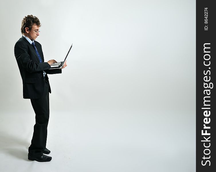 Young businessman standing up and using laptop, free space. Young businessman standing up and using laptop, free space